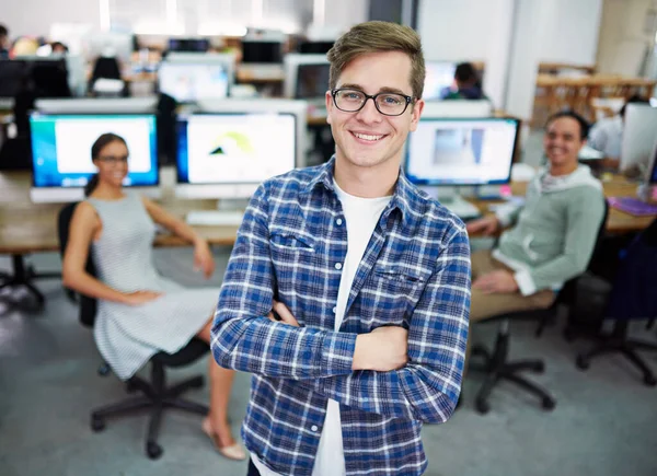 Theyre gifted young pros. Portrait of a young man standing in an office with designers in the background