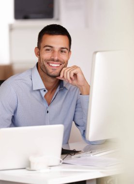 En iyi sonuçları vereceğine güvenebilirsin. Gülümseyen genç bir adam bilgisayar ekranının arkasında oturuyor.