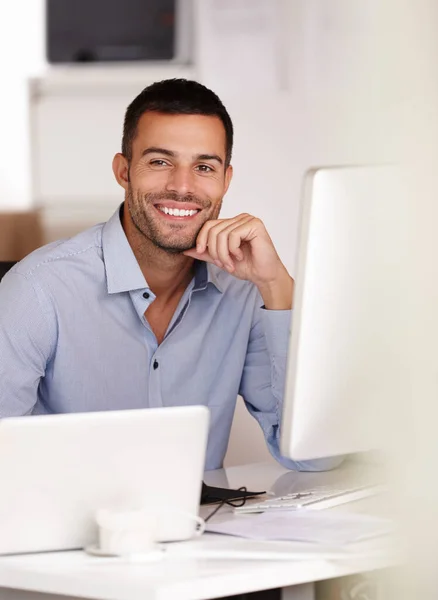 You can trust him to deliver the best results. a smiling young man sitting behind a computer screen