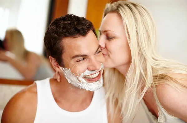 stock image I adore my man. A handsome happy man with shaving cream on his face with his girlfriend kissing his cheek