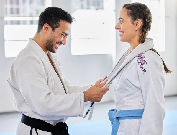 Karate, belt and martial arts coach happy with fitness, workout and taekwondo student progress. Sports training achievement, ceremony and win of a woman after a fight exercise in a health gym studio.