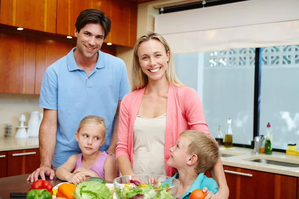 Choosing the healthy option. Portrait of a happy family of four standing behind a kitchen counter filled with healthy food