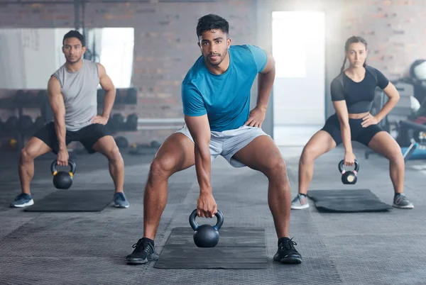 Fitness, kettlebell weight and people doing an exercise for strength, wellness or health together in a gym. Sports, motivation and athletes doing a squat workout with personal trainer in sport studio.