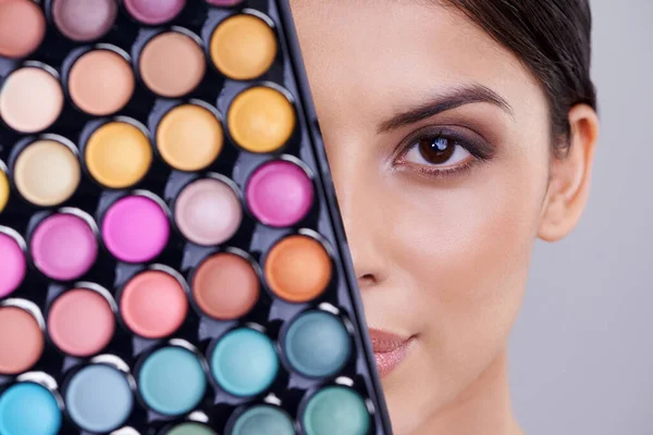 Colors to go with every mood. Studio shot of a beautiful woman with makeup palettes in front of her face