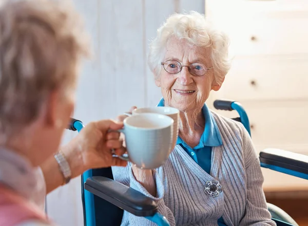 高齢者の女性は 幸せな友人やトーストコーヒー車椅子で部屋 家や老人ホームで一緒に 高齢者の女性 愛のためのマグカップと笑顔 幸福と障害のある家庭での結合とケア — ストック写真