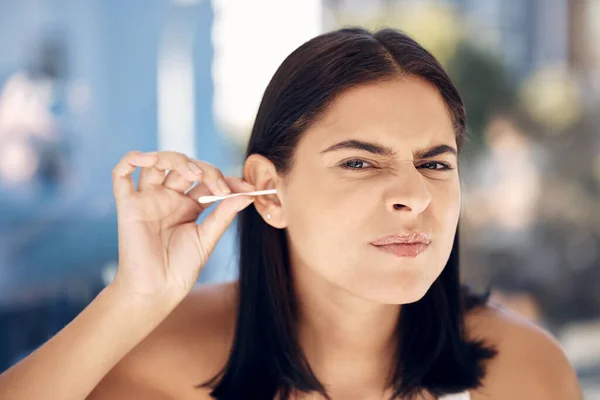 stock image Ear, cleaning and woman in a bathroom for grooming, hygiene and daily routine with cotton buds on blurred background. Face, girls and earwax removal for wellness, gresh and body care in India.