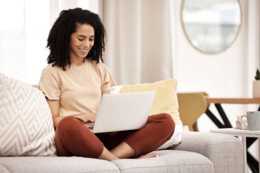 Siyahi bir kadın, çalışma ve dizüstü bilgisayarla oturma odasında yazarak mutlu çalışma araştırmaları yapıyor. İnternet planlaması ve dijital pazarlama üzerine çalışan uzaktan kumandalı serbest çalışan bir ev bilgisayarında gülümseyen.