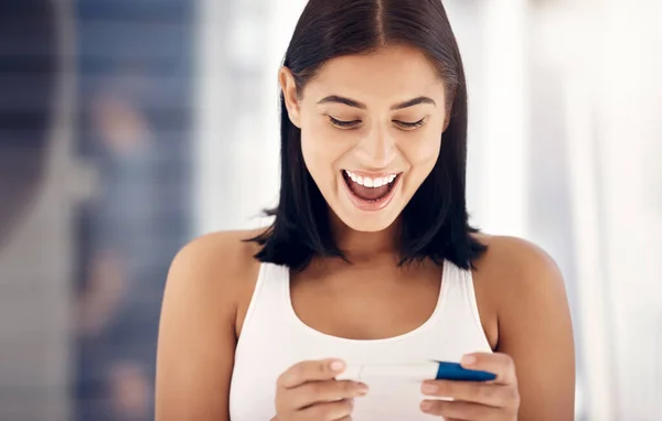 Excited, smile and woman with positive pregnancy test results with happy expression on face in bathroom. Family, love and pregnant girl with excitement for baby, child and future motherhood at home.