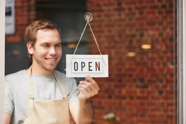 Open sign, startup and small business owner in coffee shop with pride and happiness to welcome people at front door of restaurant. Happy entrepreneur ready for service at cafe or retail store.