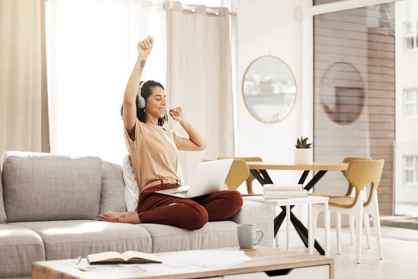 stock image Music, laptop and woman dance on sofa streaming audio podcast, radio sound or digital online playlist. Work from home, wellness and relax designer listening to download song on fun break.