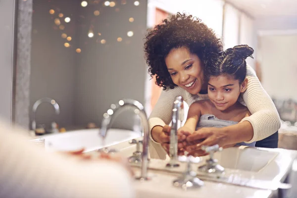 Teaching her the importance of washing your hands. a mother and daughter washing their hands at the bathroom sink