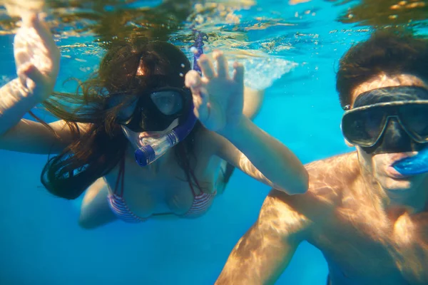 水生の美しさに飲み込まれた ターコイズブルーの海でシュノーケリングをしている若いカップルが — ストック写真