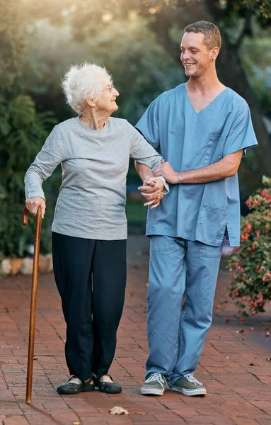 看護師 高齢者の女性と健康と健康のために公園を歩く 理学療法 リハビリテーション 退職した高齢女性障害者と庭の屋外で医療従事者と話す杖 — ストック写真