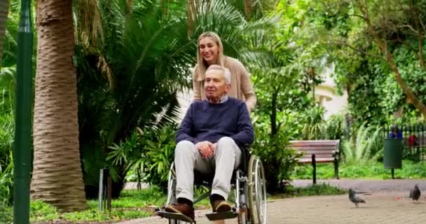 オーストラリアの緑の庭で自然の中で車椅子で父親と散歩中の女性 運動や新鮮な空気のための屋外公園で大人の娘と一緒に歩く障害のある高齢者 — ストック動画