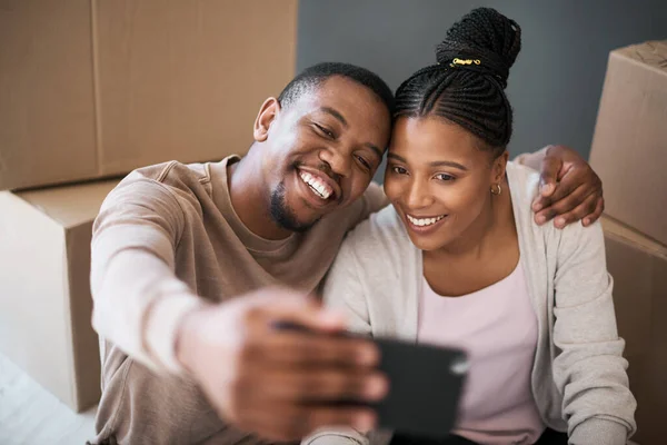 Phone, couple and selfie while moving in to home, real estate or apartment, happy and proud on a floor. New house, property and man with woman on a living floor for picture, moment and bonding.