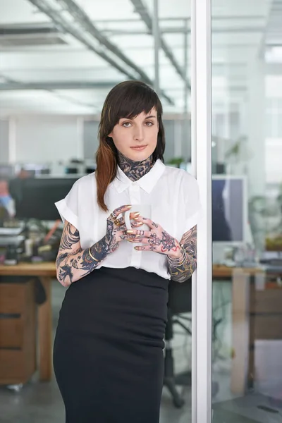 Stereotypes - who needs em. A cropped shot of a tattooed businesswoman standing in her office with a cup of coffee