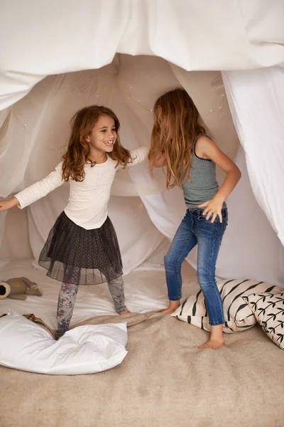 在毛毯堡垒里跳舞两个妹妹在屋里玩耍 — 图库照片