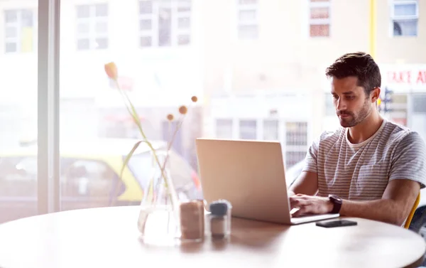사무실을 구경하는 카페에서 노트북으로 일하는 젊은이 — 스톡 사진