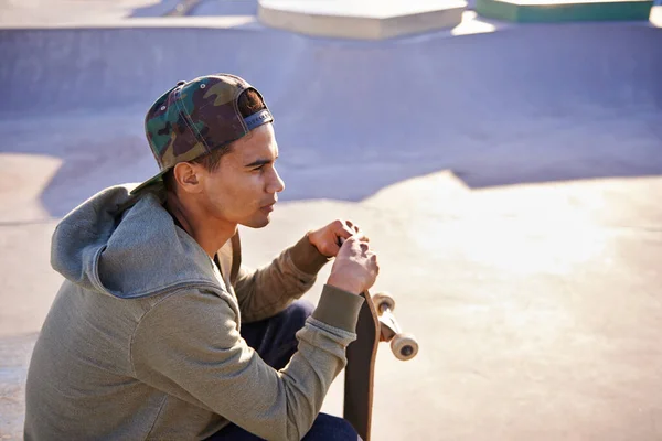 他最喜欢的地方思考 一个年轻的滑板手坐在一个滑板公园里 — 图库照片