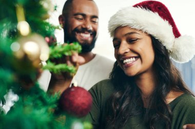 Noel, ağaç ve gülümseme, şenlik sezonu için evi birlikte dekore eden siyah bir çiftle. Aşk, kutlama ve tatiller Noel Baba şapkalı mutlu bir adam ve kadınla bir evde kaynaşırken.