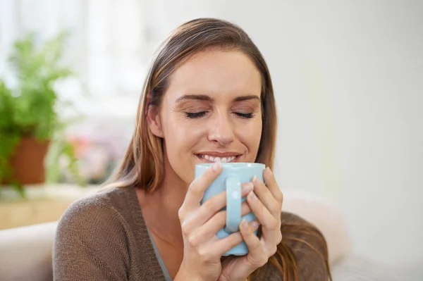 stock image The smell of fresh coffee. an attractive woman drinking coffee while sitting on the sofa