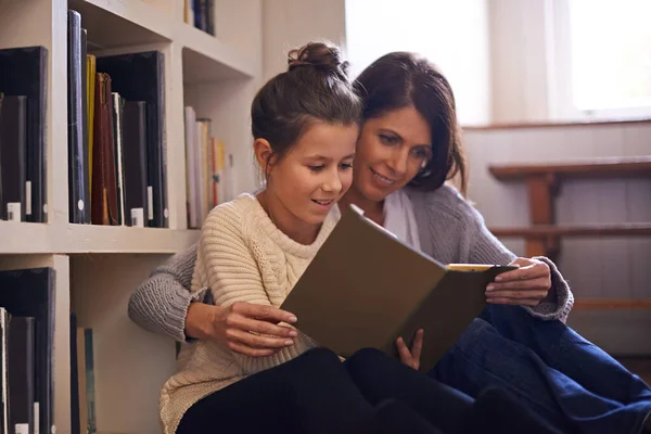 The whole family loves books. A mother and daughter reading a book together at home