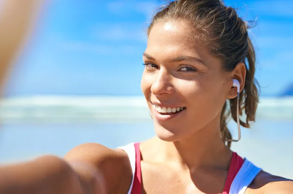 自私自利 带耳机的女人 为了音乐和锻炼的动机 在海滩上微笑 在蓝天的大自然里 快乐的户外图片 听播客在锻炼 积极的生活形象 — 图库照片