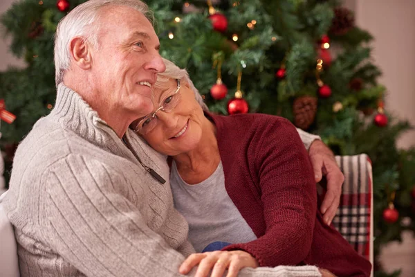 stock image Christmas, love and senior couple hug on sofa in home, affection and bonding. Romance, xmas holiday and happy elderly, retired woman and man embrace on couch enjoying quality time together in house.