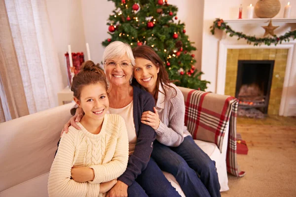 Grandmother, mother and girl on sofa at Christmas enjoying holiday, vacation and festival celebration. Family, love and and portrait of mom bonding with grandma and child with Christmas tree in home.