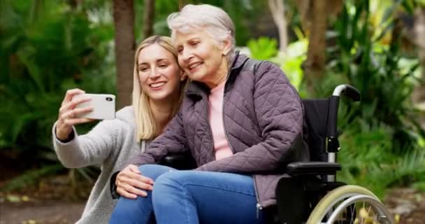 老年妇女 女儿和自理能力强的人在户外公园与坐轮椅的老年人一起进行康复 并与收容所或护理人员一起呼吸新鲜空气 成年人 在英国 孩子和年迈的母亲带着手机拍照 — 图库视频影像