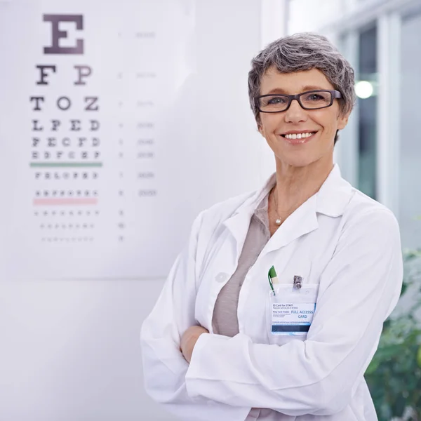 让我们为你找一副完美的眼镜 一位女性视光师站在眼试海报旁边的画像 — 图库照片