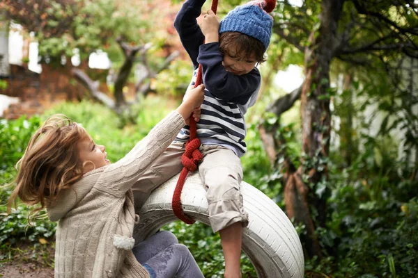 ターザンとジェーン 2人のかわいい子供が庭でタイヤのスイングで遊んでいます — ストック写真
