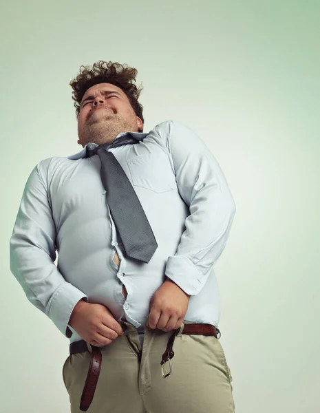 ほとんど閉じて 太りすぎのビジネスマンのユーモアのあるスタジオショット彼のパンツをボタンしようとしている — ストック写真