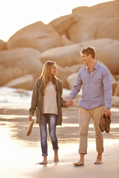 日没時に散歩 幸せな若いカップルが夕日のビーチでロマンチックな散歩を楽しんでいます — ストック写真