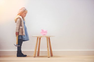 Learning about the importance of saving. A little girl standing next to her piggy bank with a hammer clipart