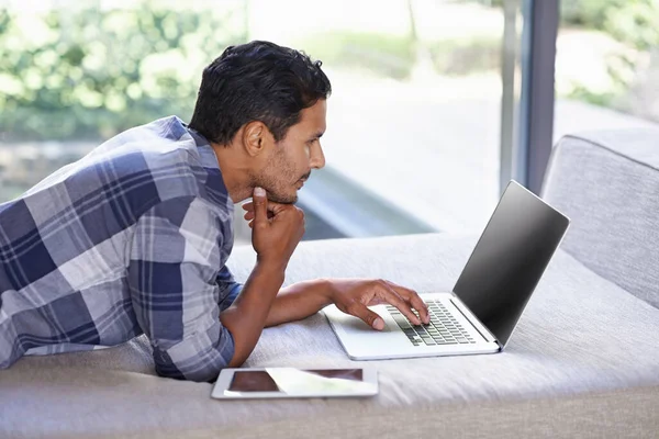 在他的业余时间上网 一个年轻人在旁边放着他的笔记本电脑和他的数码平板电脑 — 图库照片