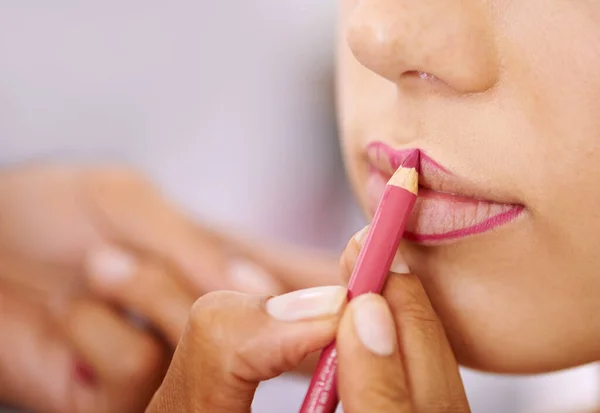 Outlining luscious lips. a woman applying colour to the outline of her lips