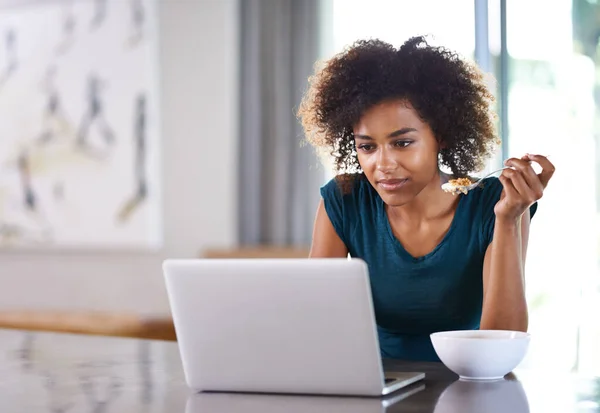 stock image Online all the time. a busy young woman eating breakfast while surfing the net