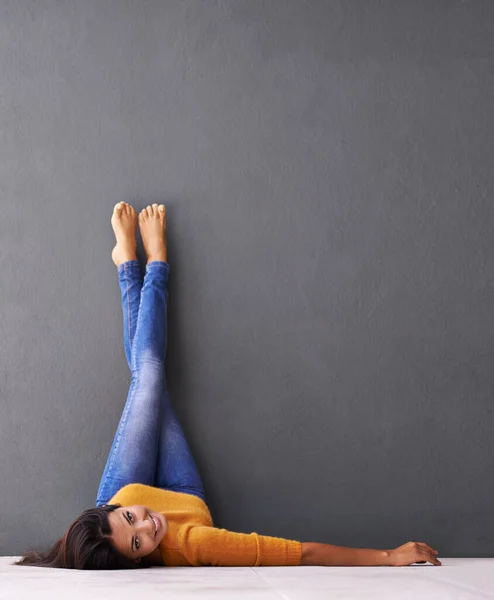 平和を 壁に足を向けて床に横になっている若い女性 — ストック写真