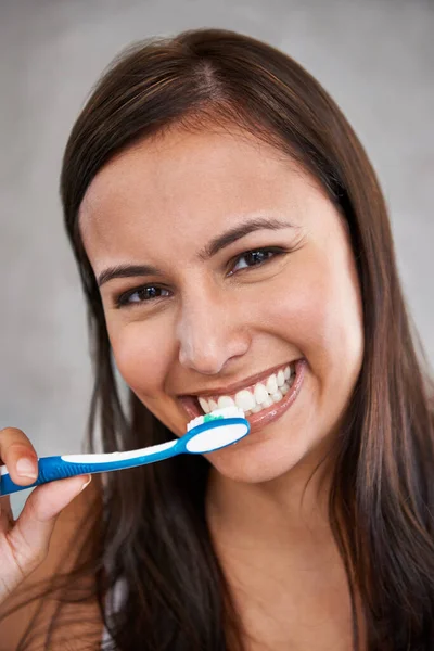 Brushing bad breath away. An isolated portrait of a young woman happily brushing her teeth