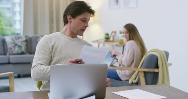 家庭のリビングルームでフィンテックのための財務 ノートパソコン 文書や書類とカップル オンライン銀行 住宅ローンの支払い 男性がアパートで税金をチェックするのを助ける女性 — ストック動画