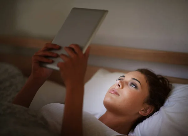 晚上在网上 一个漂亮的年轻女人在床上用平板电脑 — 图库照片