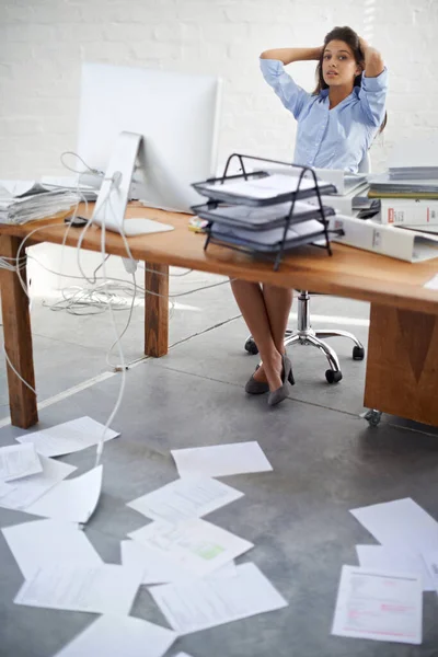 OK. Maybe its time to get organized...A young businesswoman sitting at her desk that is full of paperwork