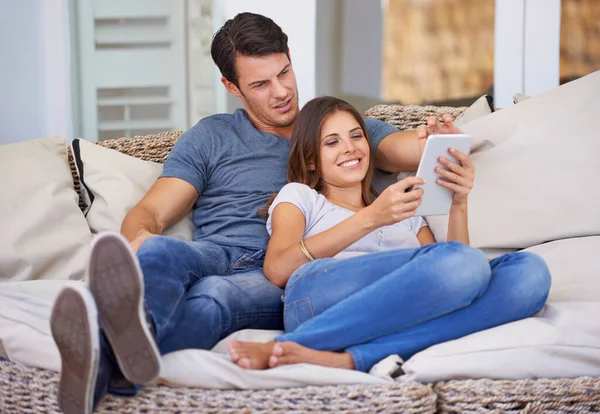 Just chilling on the couch. An affectionate young couple relaxing at home with a digital tablet