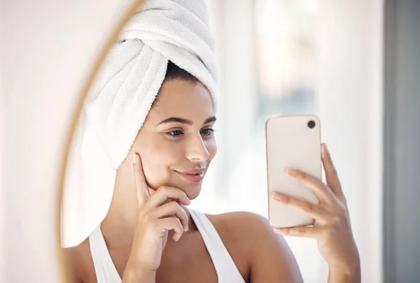 Mirror selfie, skincare and woman with phone for beauty, facial cleaning and hair care in a bathroom. Social media, self care and face reflection of a girl with a photo on a mobile of morning routine.