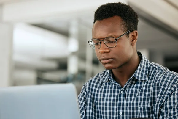 Thinking, black man and laptop for business, online reading and search internet in office. Young male, entrepreneur and computer for trading, concentration or focus for research, stress and workplace.