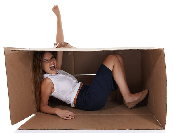 Im breaking outta here. A young woman breaking through a cardboard box shes trapped in while isolated on white