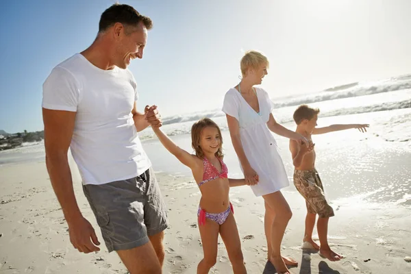 まだ泳ぐ準備ができている 幸せな若い家族が一緒に太陽の下でビーチを歩いている — ストック写真