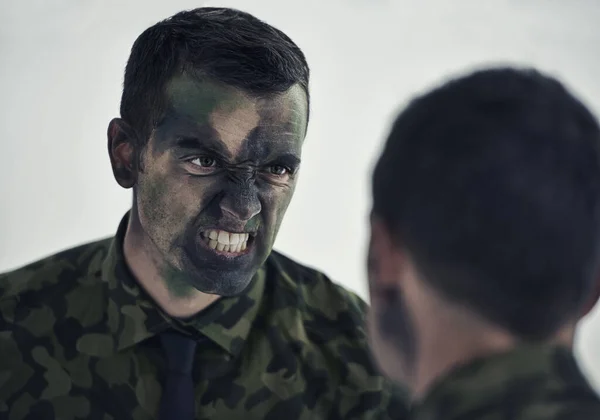 戦争の準備だ 鏡を見ながら平均的な顔をして顔をカモフラージュした軍の男 — ストック写真