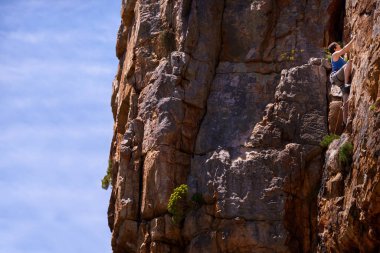 She thrives on risk... thats why she likes rock climbing. a female climber scaling a rock face clipart